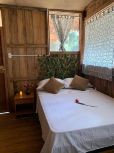 1 dormitorio con 1 cama blanca grande y ventana en PAMPA HERMOSA LAKE RESORT en Puerto Maldonado
