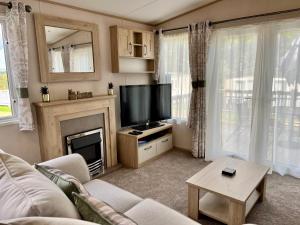 ein Wohnzimmer mit einem TV und einem Kamin in der Unterkunft 3 Bedroom Caravan MC34, Lower Hyde, Shanklin, Isle of Wight in Shanklin