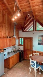 cocina con armarios de madera, mesa, mesa y sillas en Cascadas del Llaima, en Refugio Llaima
