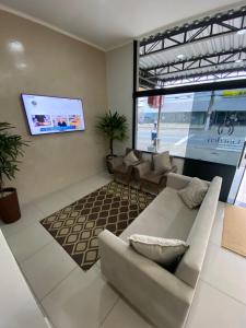 ein Wohnzimmer mit einem Sofa und einem Flachbild-TV in der Unterkunft Garden Hotel in Aparecida