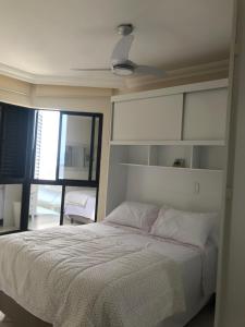 1 dormitorio con 1 cama con cabecero blanco en Lindo apartamento com vista para o mar, en Matinhos