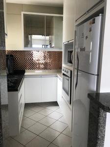 Lindo apartamento com vista para o mar في ماتينيوس: مطبخ مع دواليب بيضاء وثلاجة