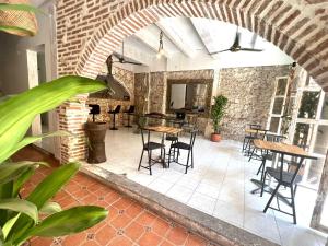 un patio avec des tables et des chaises et un mur en briques dans l'établissement Pachamama Hostel, à Carthagène des Indes
