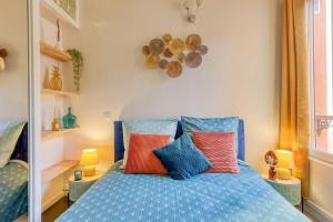 a bedroom with a blue bed with colorful pillows at Escale à Paris Metro & Parking in Saint-Ouen