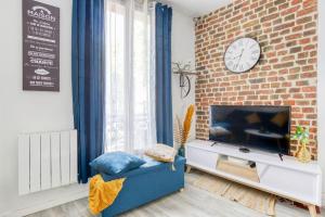 a living room with a tv and a brick wall at Escale à Paris Metro & Parking in Saint-Ouen
