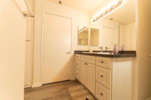 La salle de bains blanche est pourvue d'un lavabo et d'un miroir. dans l'établissement Cozy Hollywood Get Away, à Los Angeles