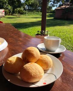 a plate of rolls on a table with a cup of coffee at Pousada Recanto do Sossego- Serra da Canastra in Vargem Bonita +18 photos