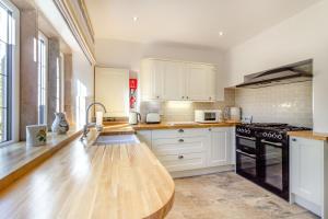 a kitchen with white cabinets and a wooden counter top at Galen Croft in Curbar