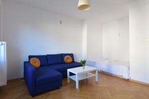 sala de estar con sofá azul y mesa en Wilcza 3 - Apartament dla 4 osób - 260m do Ambasady USA - Duży balkon od strony dziedzińca - Wifi - Good Apartments, en Varsovia