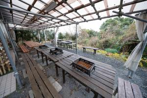 een groep picknicktafels en banken onder een pergola bij iseshima youth hostel in Shima
