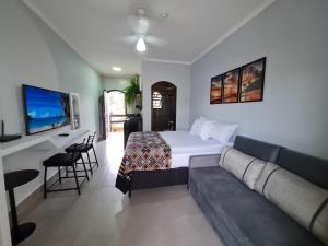 a hotel room with a bed and a couch at Cond loft novo à 400 m da praia in São Sebastião