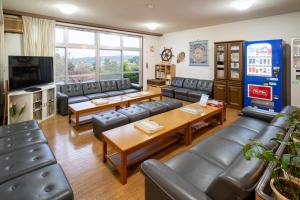 a waiting room with couches and a tv at iseshima youth hostel in Shima