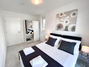 - une chambre avec un grand lit blanc et des oreillers noirs et blancs dans l'établissement Fantasy View Villa, à Novalja