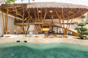 un complejo con piscina y techo de paja en Clan Living - The Founder Ubud en Ubud