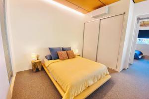 a bedroom with a bed with yellow sheets and blue pillows at Dune Ten by Kingscliff Accommodation in Fingal Head