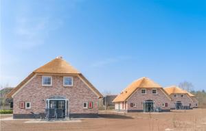 twee gebouwen met rieten daken en stoelen voor hen bij Gorgeous Home In Den Ham With Sauna in Den Ham