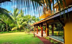 un edificio con un patio verde y palmeras en Villa Bora Bora - Frente mar, Praia do Forte, en Praia do Forte