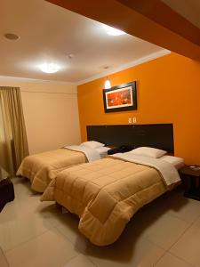 2 camas en una habitación de hotel con paredes de color naranja en Royal Garden Hotel, en Lima
