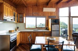 a kitchen with wooden cabinets and a table with chairs at The Boomerangs at Johanna on the Great Ocean Road in Johanna