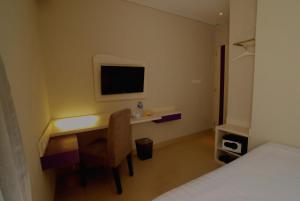a bedroom with a desk with a chair and a television at Vio Westhoff in Bandung