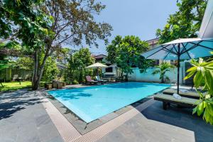 una gran piscina con sombrilla y sillas en The Country House by Class6, en Hoi An
