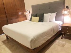 ein Schlafzimmer mit einem großen Bett mit weißer Bettwäsche und Kissen in der Unterkunft 206 Amena Boho Modern Oasis Best Location&Fast WIFI in Tulum