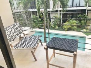 einen Balkon mit 2 Stühlen und einem Pool in der Unterkunft 206 Amena Boho Modern Oasis Best Location&Fast WIFI in Tulum