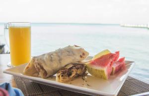 a plate of food with fruit and a glass of orange juice at Blue Marlin Beach Resort in Dangriga