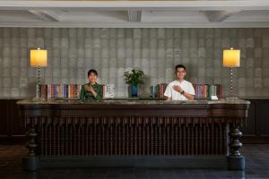 due persone in piedi dietro un bancone in una stanza di La Siesta Hoi An Resort & Spa a Hoi An