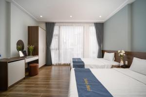 a hotel room with two beds and a desk at Melody Hotel in Da Nang