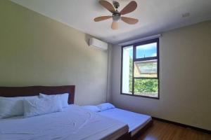 a bedroom with a bed with a ceiling fan and a window at Beachfront Vacation Villa with Infinity Pool in Batangas City