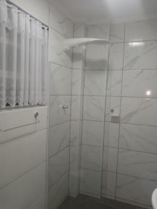 a bathroom with a glass shower with white walls at Apartamento São Vicente in São Vicente