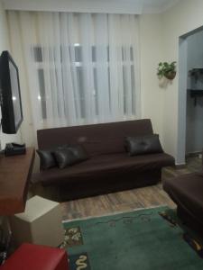 a living room with a brown couch in front of a window at Apartamento São Vicente in São Vicente