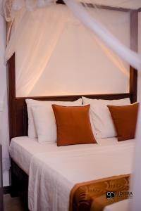 a bedroom with a bed with orange and white pillows at Blooming polhena in Matara