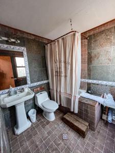 a bathroom with a toilet and a sink and a tub at Punta Ballena Lodge in Pichilemu