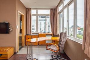 Cette chambre comprend une table, une chaise et des fenêtres. dans l'établissement Hanoi Golden Sunshine Villa Hotel and Travel, à Hanoï