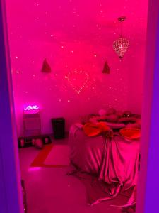 um quarto rosa com uma cama e um tecto rosa em Jacuzzi Appartement love room em Freneuse