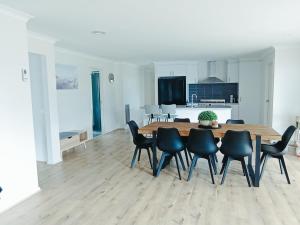 a kitchen and dining room with a wooden table and chairs at Captains Edge- Brand New 3 bedroom spacious home, private afresco & yard central to Paynesville CBD in Paynesville