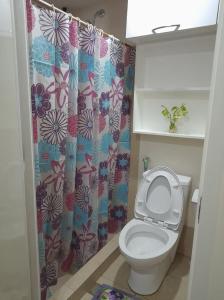 a bathroom with a toilet with a flower shower curtain at Stanford Suites 2 Lilian in Silang