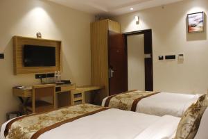 Habitación de hotel con 2 camas, escritorio y TV. en Mango Hotels Vijayawada en Vijayawāda