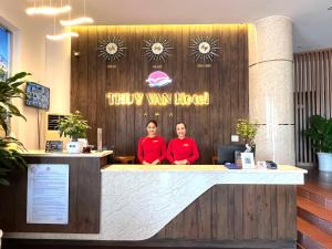 Deux femmes se tenant derrière un comptoir dans un hôtel de camionnettes heureux dans l'établissement Thuy Van Hotel, à Vung Tau