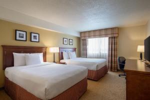a hotel room with two beds and a television at Travelodge Suites by Wyndham Regina - Eastgate Bay in Regina