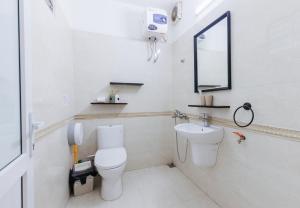 a white bathroom with a toilet and a sink at Legume House - 30m to centre in Hanoi