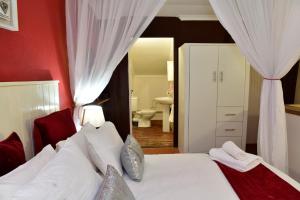 a bedroom with a white bed with a red wall at Villa Moria Romance in Dullstroom