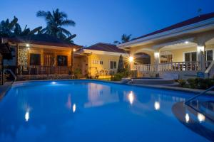 a swimming pool in front of a house at night at Alona Austria Resort in Panglao