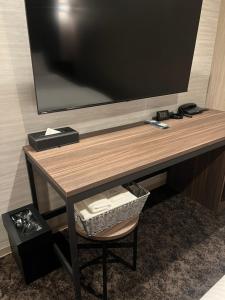 a desk with a television on a wall with a chair at HOTEL GrayⅡ in Osaka