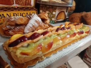 - un gâteau avec des fruits et des noix sur une étagère avec des pâtisseries dans l'établissement City View Pescara B&B, à Pescara