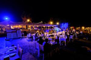 een groep mensen die 's nachts aan tafel zitten bij Herodot Beach Otel in Mugla