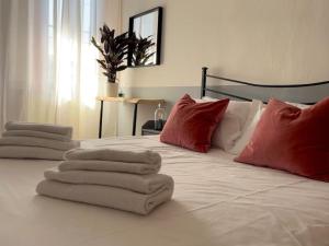 Una cama blanca con almohadas rojas y toallas. en 2-bedroom flat in the heart of Bergamo city centre, en Bérgamo