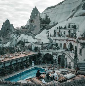 a group of people sitting around a pool in front of a mountain at Local Cave House Hotel in Göreme
